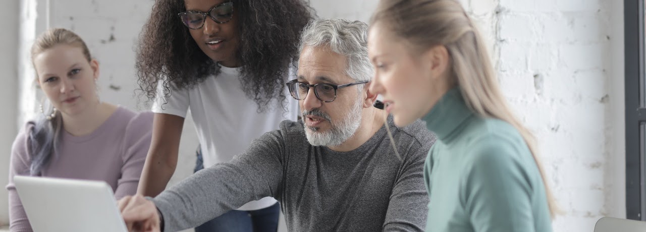 four people observing a laptop screen